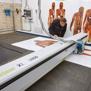 Großformatige bedruckte Acrylglasplatte bei der präzisen Laserbearbeitung in der Produktion der Gubener Plastinate GmbH mit einer eurolaser Laserschneidmaschine