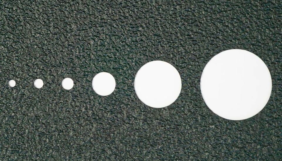 CO₂ laser system cutting precise circles in different sizes into non-slip Safety Track® material