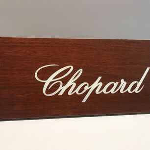 Letras de acrílico integradas en una placa de madera con el logotipo de la marca Chopard