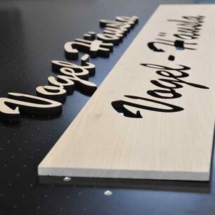 Geschwungener Schriftzug aus Holz als Beispiel für das Laserschneiden von Holz auf Laserschneidmaschinen von eurolaser