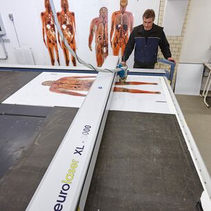 Mitarbeiter der Gubener Plastinate GmbH beim präzisen Laserschneiden von bedrucktem Acrylglas mit einer eurolaser Laserschneidmaschine in der Fertigung